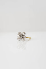 A close-up of a modern cabinet knob with a sculptural design featuring polished nickel spheres and a brass screw base.