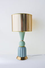 Close-up of a handmade mint green and aqua ceramic table lamp with a fluted aqua base, smooth mint taper detail, and polished gold drum lampshade. Features brushed brass hardware and a sculptural mid-century modern design perfect for living rooms, bedrooms, or stylish desks.