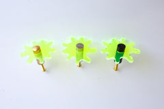 Close-up view of a single Splat drawer pull in transparent neon green acrylic with a brass detail, highlighting its splat-shaped design and high-quality materials.