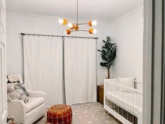 Neutral nursery design with an orange and brass midcentury modern style chandelier
