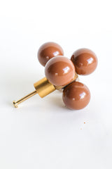 An oversized decorative drawer pull featuring five glossy fudge brown spheres arranged around a solid brass cube. The cube is mounted to a brushed brass stem and screw, designed for installation on cabinets or drawers. The geometric design and mixed materials give it a sculptural, modern look with a midcentury flair. Photographed on a clean white background.