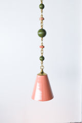 Peach, Olive, & Rose Marble Beaded Pendant Light hanging against a white wall, showing sculptural beaded chain and soft peach cone shade.