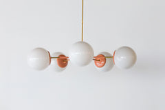 Peach & Brass modern chandelier. Mid Century modern style with oversize white globe shades.  Large Statement light for colorful interiors.  Adds a pop of color and can be customized.