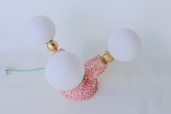 Close-up of the glossy, bumpy, bubblegum-pink glaze on this one-of-a-kind sculptural ceramic lamp, highlighting the hand-built texture, pastel pink underglaze, and 1-inch raw brass spheres that connect to glowing G9 bulbs—perfect for fans of offbeat, creature-inspired home accents and modern handmade lighting.