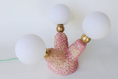 Side angle of a handmade ceramic creature lamp with a pink spiky finish, branching organic shape, brass hardware, and mint green cord with inline switch, offering soft ambient lighting for shelves, side tables, or unusual vignettes in eclectic, design-forward homes.