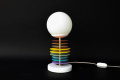 This Vertebrale lamp, designed by Sazerac Stitches, features powder-coated steel discs stacked in a vibrant gradient of colors. Topped with a frosted globe and anchored by a polished marble base, it’s a perfect blend of art and function.