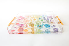 Side view Handmade acrylic tray featuring real dried and pressed flowers arranged in a rainbow gradient layout, with modern gold handles on either side. The flowers are suspended in clear resin, creating a vibrant, colorful design that is perfect for spring decor. Ideal for use as a vanity tray, coffee table tray, or bar accessory in bright, eclectic, or cottage-inspired interiors.