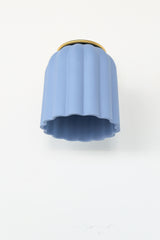 Unglazed soft blue ceramic wall sconce with solid brass hardware, featuring a scalloped silhouette that brings a charming touch to bathroom and powder room lighting; ideal for traditional, coastal, Nantucket-inspired, Southern, or transitional interiors where soft color and timeless form add a refined yet playful focal point.