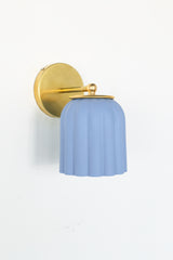 Unglazed soft blue ceramic Marcella wall sconce with fluted scalloped shade and brushed brass backplate; a handmade fixture perfect for bathrooms, bedside lighting, or hallways in traditional, coastal, Southern, grandmillennial, Nantucket-style, cottagecore, transitional, or vintage-inspired interiors.