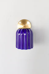 Marcella ceramic wall sconce in high-gloss glazed cobalt blue with brushed brass hardware, featuring a fluted silhouette and jewel-toned finish. This bold statement light blends classic craftsmanship with modern maximalist style—ideal for traditional powder rooms, eclectic interiors, or coastal-inspired spaces seeking a vibrant pop of color.