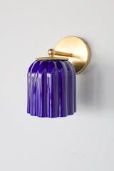 Marcella ceramic wall sconce in high-gloss glazed cobalt blue with brushed brass hardware, featuring a fluted silhouette and jewel-toned finish. This bold statement light blends classic craftsmanship with modern maximalist style—ideal for traditional powder rooms, eclectic interiors, or coastal-inspired spaces seeking a vibrant pop of color.