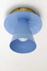 Modern & Geometric Color Saturated wall sconce or ceiling flushmount light fixture shown in pastel blue but available in over 30 curated colors.  Make a bold statement as bathroom wall lighting or in a small space as a ceiling light.  Consists of a geometric cone shade.  Maximalist and chunk wall sconce or ceiling light fixture in bold colors perfect for color-lovers, minimalists that embrace color, kids spaces, and more.  The Sonny sconce is designed and made in New Orleans.