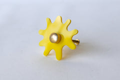 Splat drawer pull in bright yellow acrylic with a brass detail installed on a colorful dresser drawer, demonstrating its easy installation and ability to add a unique touch.
