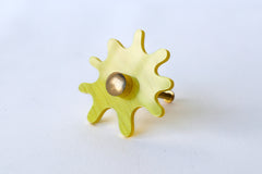 Splat drawer pull in yellow pearl acrylic with a brass detail installed on a colorful dresser drawer, demonstrating its easy installation and ability to add a unique touch.