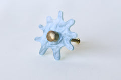 Splat drawer pull in pastel pearl blue acrylic with a brass detail installed on a colorful dresser drawer, demonstrating its easy installation and ability to add a unique touch.