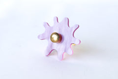 Splat drawer pull in pastel pink pearl acrylic with a brass detail installed on a colorful dresser drawer, demonstrating its easy installation and ability to add a unique touch.