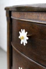 Splat drawer pull in white pearl acrylic with a brass detail installed on a colorful dresser drawer, demonstrating its easy installation and ability to add a unique touch.