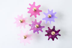 Multiple Splat drawer pulls in various finishes like pink and arranged on a white background, showcasing their versatility and playful character.