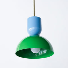 Close-up of the Taeuber Pendant in hydrangea blue and spring green by Sazerac Stitches, showcasing its glossy powder-coated finish and sculptural double-dome silhouette. The pendant’s playful color pairing highlights the brand’s modern take on midcentury design, handcrafted from powder-coated steel with a brass downrod. Ideal for kitchens, dining rooms, or breakfast nooks, this colorful pendant light adds a vibrant, artistic touch to contemporary and eclectic interiors.