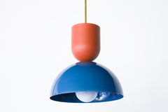 Close-up of the Taeuber Pendant in denim blue and terra cotta by Sazerac Stitches, featuring a glossy two-tone powder-coated finish and brass downrod. The pendant’s sculptural, midcentury-inspired silhouette highlights the contrast between the matte terra cotta top and the reflective deep blue dome, showcasing expert craftsmanship and bold color design. Perfect for kitchens, dining nooks, or creative interiors, this handmade pendant light adds a modern, artful touch to colorful and contemporary spaces.