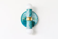 A handcrafted Teal and Grey Marbled Thalia Sconce with dual bulbs, shown against a white wall. The fixture features swirling marbled enamel in soft teal and grey, paired with warm brass hardware. Ideal for modern bathrooms, vanities, or entryways seeking a pop of bold, artistic lighting.