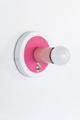 Colorblocked pink and white wall sconce with a chrome toggle on-off switch