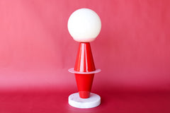 Inspired by Bauhaus design principles, the Totem Lamp by Sazerac Stitches features striking geometric forms in red and pink powder-coated steel, a frosted globe, and a marble base, perfect for contemporary interiors.