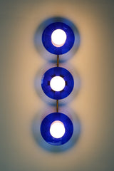Bright Blue Triple Circus Sconce: Bold and dazzling, the Bright Blue Triple Circus Sconce captures the essence of Murano glass with its vibrant blue acrylic disc. Each intricately etched disc casts mesmerizing light and shadow patterns, transforming your walls into a captivating display.