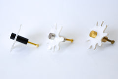 Close-up view of a single Splat drawer pull in white pearl acrylic with a brass detail, highlighting its splat-shaped design and high-quality materials.