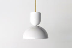 lose-up of the Taeuber Pendant in bright white by Sazerac Stitches, showcasing its sculptural double-dome silhouette and glossy powder-coated finish with a brass downrod. This modern, handmade pendant light highlights the bold color and smooth craftsmanship of the design, perfect for kitchens, dining nooks, and modern interiors seeking a pop of color and midcentury-inspired style.