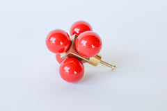 A sculptural brass hardware piece with five glossy red spheres, displayed on a clean white background.