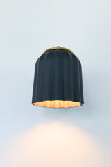 Marcella wall sconce with unglazed matte black ceramic shade and brushed brass backplate, shown on a neutral background. The scalloped silhouette and soft finish evoke timeless elegance with a modern edge, perfect for moody interiors, modern traditional decor, or eclectic spaces seeking contrast and sophistication.