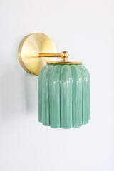 Glazed jade green ceramic Marcella sconce with fluted scalloped shade and brushed brass hardware; a handcrafted wall light ideal for bathrooms, powder rooms, or hallways in traditional, Southern, coastal, cottagecore, New England prep, grandmillennial, vintage-inspired, Art Deco, eclectic, or transitional interiors.