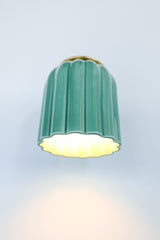 Glossy jade green ceramic wall sconce with fluted detailing and a brushed brass backplate, shown against a light gray background. This handcrafted fixture blends classic charm with playful color, ideal for Southern traditional, vintage-inspired, or coastal interiors seeking a subtle pop of green.