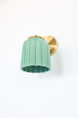 Glazed jade green ceramic Marcella sconce with fluted scalloped shade and brushed brass hardware; a handcrafted wall light ideal for bathrooms, powder rooms, or hallways in traditional, Southern, coastal, cottagecore, New England prep, grandmillennial, vintage-inspired, Art Deco, eclectic, or transitional interiors.