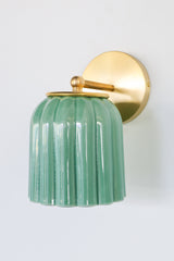 Glazed jade green ceramic Marcella sconce with fluted scalloped shade and brushed brass hardware; a handcrafted wall light ideal for bathrooms, powder rooms, or hallways in traditional, Southern, coastal, cottagecore, New England prep, grandmillennial, vintage-inspired, Art Deco, eclectic, or transitional interiors.