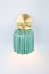 Glossy jade green ceramic wall sconce with fluted detailing and a brushed brass backplate, shown against a light gray background. This handcrafted fixture blends classic charm with playful color, ideal for Southern traditional, vintage-inspired, or coastal interiors seeking a subtle pop of green.