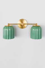 This handcrafted double sconce from Sazerac Stitches combines ribbed ceramic shades in jade green with brass accents, delivering character and elegance to any space.