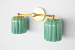 Distinctive ribbed ceramic shades in jade green paired with brass hardware. The Marcella Double Sconce offers warmth, texture, and artistry for modern and eclectic interiors.