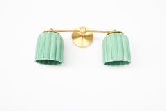 Add a pop of color with the Double Marcella Sconce. Featuring hand-glazed jade green shades and a warm brass mount, this piece blends mid-century inspiration with contemporary design.