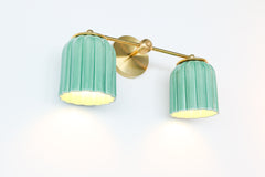 A signature piece from Sazerac Stitches, this Marcella Double Sconce combines hand-glazed jade green ceramic with brass for an elegant yet playful lighting design.