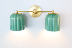 Distinctive ribbed ceramic shades in jade green paired with brass hardware. The Marcella Double Sconce offers warmth, texture, and artistry for modern and eclectic interiors.