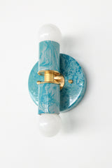 Close-up view of the Teal and Grey Marbled Thalia Sconce, a modern double-bulb wall light featuring hand-marbled teal and grey enamel with solid brass accents. This sculptural lighting fixture blends artistic flair with function, making it a standout in bathrooms, powder rooms, or hallways.