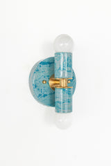 A handcrafted Teal and Grey Marbled Thalia Sconce with dual bulbs, shown against a white wall. The fixture features swirling marbled enamel in soft teal and grey, paired with warm brass hardware. Ideal for modern bathrooms, vanities, or entryways seeking a pop of bold, artistic lighting.