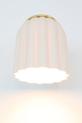 Unglazed white porcelain Marcella sconce with warm brass accents, featuring a fluted ceramic shade and classic rounded backplate. Ideal for transitional interiors, coastal cottages, and Southern-style homes, this handmade light fixture adds refined texture and soft elegance to bathrooms, bedrooms, or hallway vignettes.