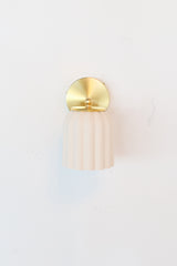 Marcella ceramic wall sconce in unglazed porcelain white with brushed brass hardware, showcasing a fluted, scalloped silhouette. This timeless fixture complements traditional, Southern-inspired, or coastal interiors with its soft matte finish and refined detailing—perfect for powder rooms, bathrooms, or hallways seeking classic charm with a sculptural edge.