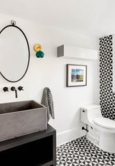 Black and white bathroom design with green and brass modern wall sconce