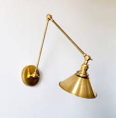 all brass industrial style sconce with a cone shade and adjustable arms perfect for open shelving
