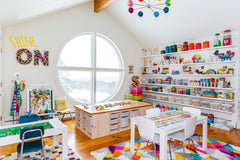 Rainbow themed playroom with crafting station, table, bins, and a big window with natural light