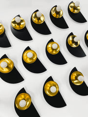 Minimalist wall sconce in rich black and luminous brass from the Kin collection. A geometric statement piece that brings sophistication and warm metallic shine to modern, classic, or eclectic interiors.
